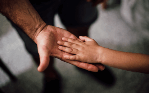 a child holdhing his dad hand